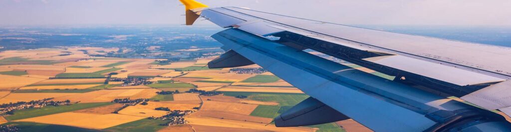 Airplane wing flying over farmland